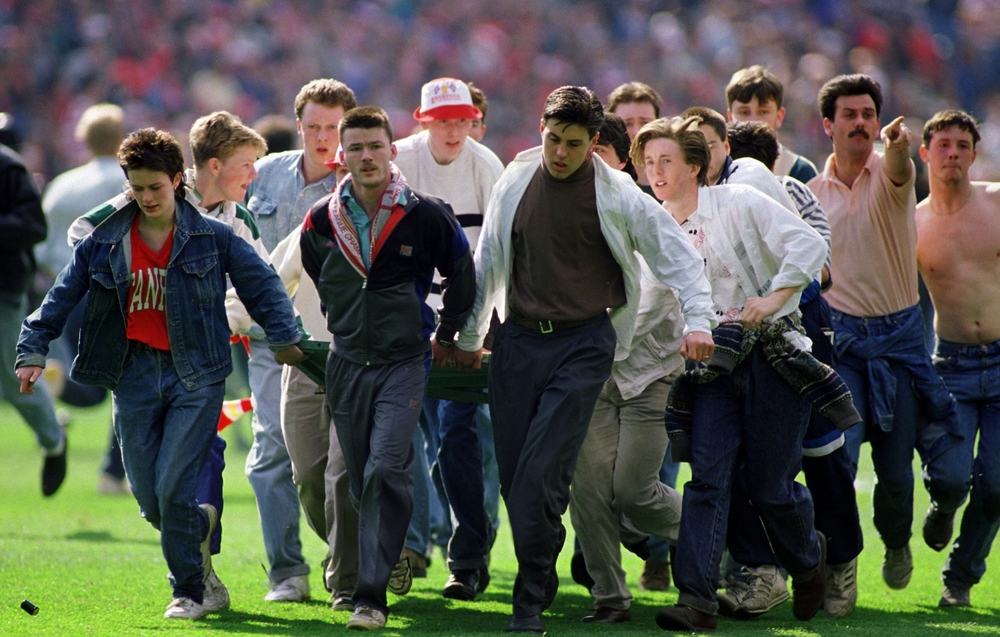 FILE PHOTO: A fan is taken from the pitch after being injured  / ACTION IMAGES